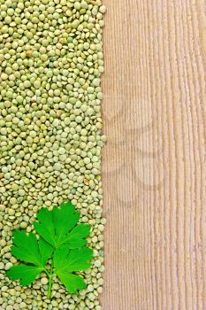 Frame of green lentils with parsley leaf on the left side of wooden boards
