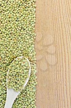 Frame of green lentils with a spoon on the left side of wooden boards