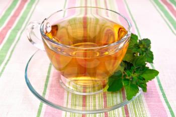 Herbal tea in a glass cup, fresh mint leaves on a background of striped linen tablecloths