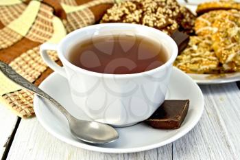 Tea in a white cup with chocolate and shortbread, napkin on a lighter background of the board