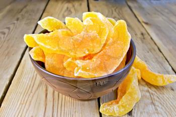 Slices of dried candied melon in a bowl on a wooden boards background