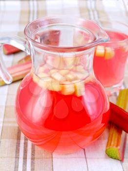 Compote from rhubarb in a glass jar and a low glassful, stems of rhubarb on a background of the tablecloth