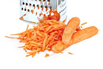 A pile of grated fresh carrots and two whole carrots, metal grater isolated on white background