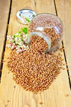 Buckwheat in a glass jar and on the table, flower buckwheat on a wooden boards background