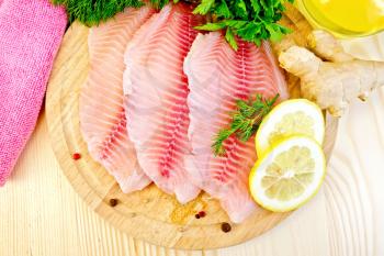 Tilapia fillets with dill, lemon, ginger, cloth, vegetable oil on a wooden boards background