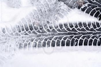 Traces of the car on a white fresh snow on the asphalt background