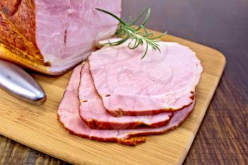 Smoked ham, slices of ham with a sprig of rosemary and dark wooden boards