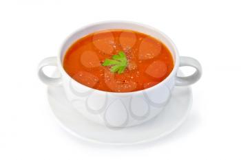Tomato soup in a white bowl with parsley and spices on a saucer isolated on a white background