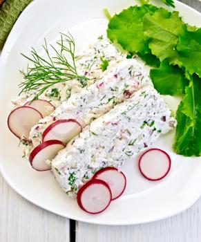 Sliced curd terrine with dill and radishes, green onions, salad on a plate, napkin on a light wooden planks on top