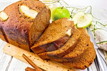 Canadian apple bread with honey and cinnamon, green apple, napkin and a knife on the background light wooden boards