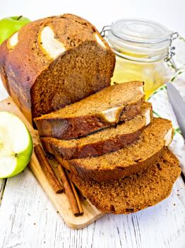 Canadian apple bread with honey and cinnamon, green apple, napkin and knife on a wooden boards background