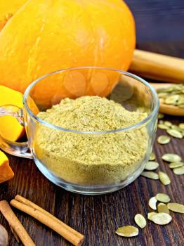 Flour pumpkin in a glass cup, rolling pin, spoon and cinnamon, fresh pumpkin, pumpkin seeds on the background of wooden boards