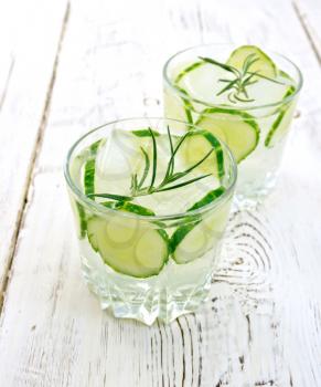 Lemonade with a cucumber and rosemary in two glassful on the background light wooden boards