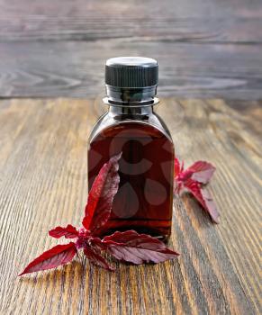One vial of oil with branch burgundy amaranth on a dark wooden board