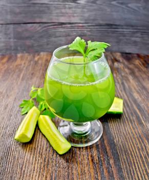 Cucumber juice in a wineglass, cucumbers and parsley on a wooden board background