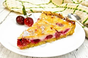 Pie with cherries and sour cream in a dish, kitchen towel with a spoon on a background of wooden boards