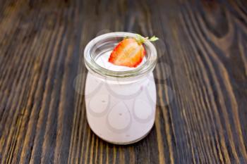Yogurt with strawberries in a glass jar on a wooden boards background