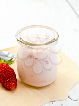 Yogurt with strawberries in a glass jar, strawberry and mint on a parchment background on wooden board