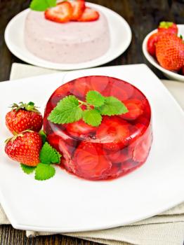 Strawberry jelly with mint and berries in the plate on the towel, panna cotta on a background of wooden boards