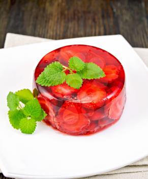 Strawberry jelly with mint and berries in a plate on a napkin on a dark wooden board