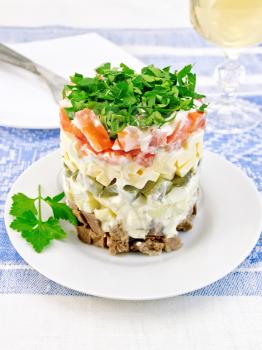 Salad with beef, boiled potatoes, pickles, cheese, tomato, parsley in the plate, glass of white wine on a background of a linen tablecloth