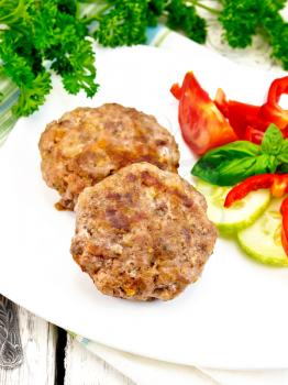 Cutlets stuffed with spinach and eggs in a dish, a salad of tomatoes, cucumber and pepper, basil and parsley on the background light wooden boards