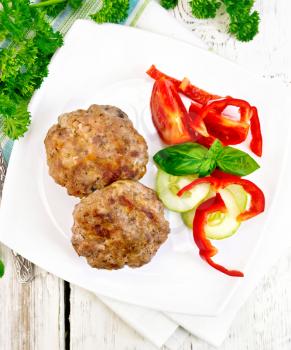 Cutlets stuffed with spinach and egg, salad with tomatoes, cucumber and pepper in a plate, basil and parsley on a background of wooden boards on top