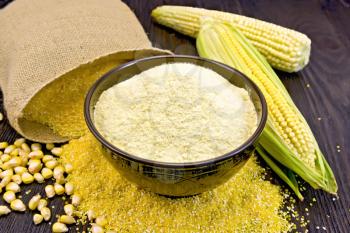 Flour corn in a bowl on the grits, cobs and grains, a bag on a wooden boards background