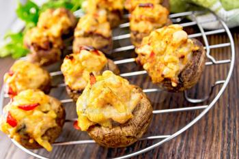 Mushrooms stuffed with meat and pepper on a metal grid on the background of wooden boards