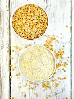 Flour pea and split pease in two white bowls on a background of wooden boards on top