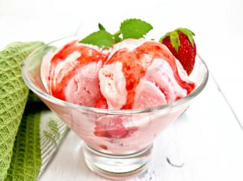 Ice cream strawberry in a glass with strawberries and strawberry syrup, napkin on a light wooden board background