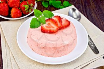 Dessert panna cotta of curd and strawberry, mint and berries in the bowl on beige napkin against the background of wooden boards