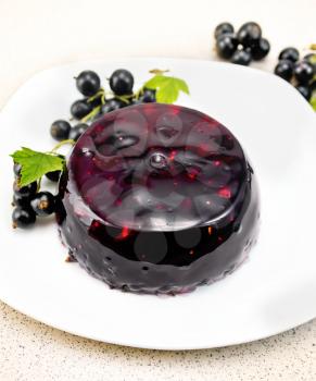 Jelly from black currant with berries in a dish on a towel on the background of a granite table