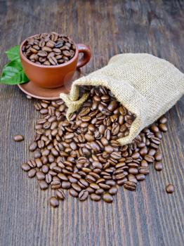 Bag of black coffee beans, brown cup on the background of a wooden board