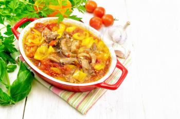 Ragout of turkey meat, tomato, yellow sweet pepper and onion with sauce in a brazier on a napkin on a light wooden board background