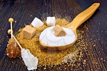 Sugar brown and white in cubes, granulated in a spoon and crystal on a stick against the background of a wooden board