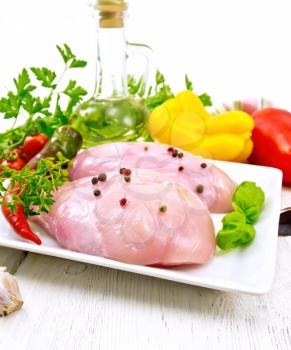 Chicken breast with hot pepper and thyme in a bowl, parsley and basil, onion, garlic and vegetables on a wooden plank background