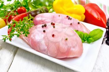 Chicken breast with hot pepper and thyme in plate, parsley, basil and vegetables on a wooden board background