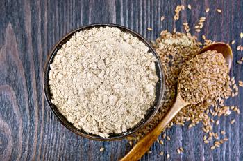 Flax flour in a bowl, seeds in a spoon and on a table on the background of a wooden board on top