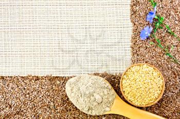 A frame of brown and white linseed, flax flour in a spoon, blue linen flowers against a rough woven fabric background