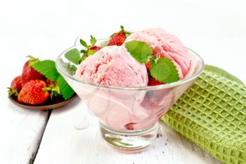 Ice cream strawberry in a glass with berries and mint, green napkin on a wooden plank background