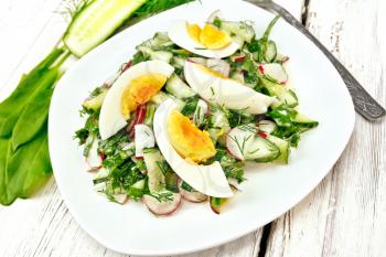 Salad of radishes, cucumber, sorrel, greens and eggs, dressed with mayonnaise and sour cream in a white plate on the background of wooden board
