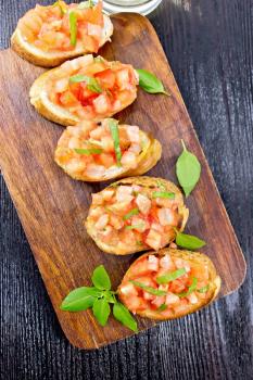 Bruschetta with tomatoes and basil on a wooden board background from above
