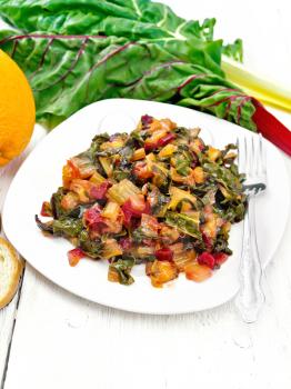 Warm chard salad with orange and onion in a plate, bread, fork on a wooden board background