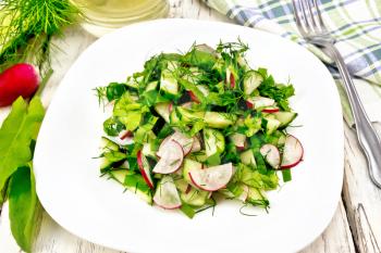 Salad from radish, cucumber, sorrel and greens, dressed with vegetable oil in a plate on the background of light wooden board