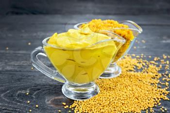 Mustard sauce and Dijon mustard in two glass saucepans, seeds on a wooden board background