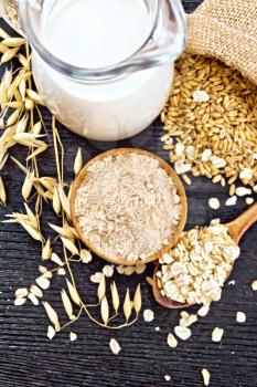 Flour oat in bowl, grain in a bag, oatmeal in a spoon, oaten stalks on the background of wooden board from above