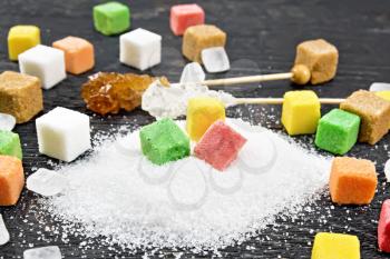 Sugar of white, brown, pink, green, yellow and different shapes on a wooden board background

