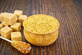 Granulated brown sugar in a bowl, crystalline on a stick and diced on wooden board background