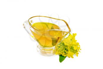 Mustard oil in a glass gravy boat, yellow mustard flowers isolated on white background